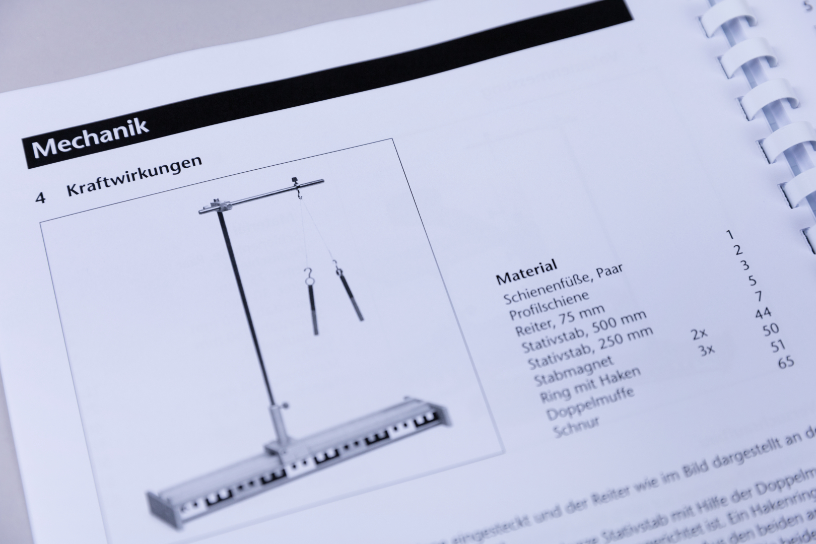 The picture shows instructions from a mechanics experiment manual that illustrates a setup for demonstrating force effects. It lists the materials needed, including rail feet, rods and other components for the experiment.