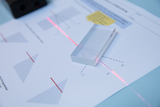 The image shows a transparent block placed on a worksheet with geometric drawings. A laser beam passes through the block and hits the worksheet to demonstrate optical phenomena such as light refraction.