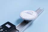 The picture shows an experimental device consisting of a protractor and a rail. The protractor is precisely scaled and allows the measurement and creation of angles for various mathematical and physical applications.