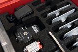 The picture shows a compact equipment for experiments, consisting of a control unit with laser module and various accessories arranged in a protective foam insert. Batteries and a power supply are also included.