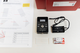 The picture shows a physics experiment set for light refraction, consisting of a laser module, a lens, a battery compartment and two batteries. There is also a worksheet with instructions on how to carry out the experiments.