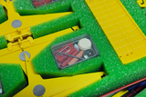 The picture shows a set for experiments, which consists of yellow plastic parts and green foam padding. In a transparent box there are various small objects such as wooden discs, paper clips and other materials for experiments.