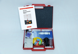 The picture shows a red box with experimental materials for teaching purposes that focus on elementary physics on the topic of heat. In the box there are various glass containers, models and a manual with instructions for experiments