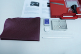 The picture shows a collection of experimental materials, including a purple piece of cloth, some test tubes, a candle, a matchbook and a metal box. These materials are arranged in a red box, accompanied by a manual with A