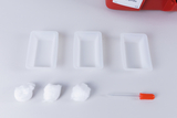 The picture shows three rectangular white containers as well as three cotton balls and a pipette with a red lid. These materials are probably intended for scientific experiments in the educational sector.