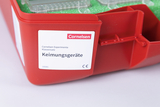 The picture shows a red box with the label &quot;Germination Devices&quot; from the Cornelsen Experimenta class set. The box contains various devices that are probably used for experiments on plant germination.