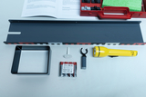 The picture shows a selection of materials for experimental purposes, including a metal plate, a square box, a flashlight and a battery pack. There is also an instruction manual and a red case with other accessories in the background.