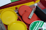The picture shows an overview of various experimental materials in a red box. You can see yellow and red lids and a metal clip, which can be used for school experiments.