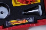 The picture shows an experiment kit with various accessories, including balls, a funnel and colorful rubber bands. The components are sorted in a red foam container, which is designed for use in the classroom.
