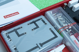 The picture shows an experiment kit from an online educational shop that contains various materials for scientific experiments. Visible are instructions, a metal connecting bracket and tools needed for the experiment.