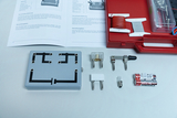 The picture shows an experimental set with various electrical components, including a circuit, fuses, wires and a battery. Next to it is an instruction manual describing how to carry out an experiment on electrical conductivity.