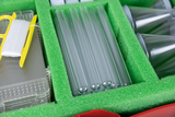 The picture shows a collection of experimental materials in a green foam insert. You can see several test tubes, some funnels and a spool of white thread, which are used for various scientific experiments