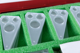 The picture shows a collection of transparent experimental devices arranged in a green foam insert. These devices have several openings and are intended for use in education, especially in scientific experiments.