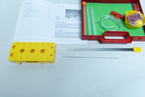 The picture shows an experiment set for investigating sound, consisting of a yellow element with holes, various tubes and a red container with accessories. There are also instructions explaining how to carry out the experiments.