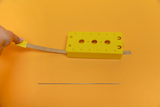 The picture shows a yellow experimental device with a flexible metal tip that is used to conduct physics experiments. Next to it is a slender metal rod that may be used as an additional component for the experiment. 