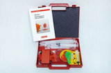 The picture shows a red box with experimental materials for elementary physics that focus on air and water. The box contains various utensils such as syringes, balloons and an experiment booklet that can be used for school projects.