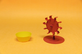 The picture shows a red colored water wheel on a stand and a yellow bowl next to it. These objects probably serve as teaching material for experiments in the field of physics or engineering.