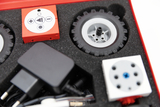 The picture shows a toolbox with various components for an experiment set, including a motor, wheels and control elements. These parts are arranged in a padded holder and offer opportunities for practical experiments in the picture