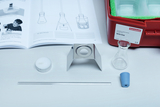 The picture shows an experiment set with various materials, including a beaker, a metal holder, a candle and a glass tube. There is also a textbook with instructions for experiments on the topic of heat.
