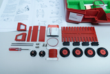 The picture shows an experiment kit for the German education system, which contains various red components, including circuits and wheels, as well as a manual for instructions. The components are arranged in a red box and offer the possibility of
