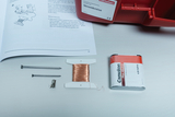 The picture shows various experiment materials, including a coil of copper wire, two nails, a connector and a battery. There is also a textbook with instructions on electrical circuits lying nearby.