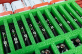 The image shows a number of experimental measuring instruments arranged in a green, foam-padded container. In the background, several batteries that can be used for the devices are visible.