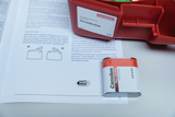 The picture shows an experiment set for electrical circuits from Cornelsen, which includes a battery and a light bulb. Next to it is an instruction manual that describes various connection options and experiments.