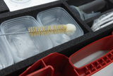 The picture shows a box with several transparent containers and a cleaning brush with a bristle brush and a softer end. In the background, other laboratory equipment used for educational experiments is visible.