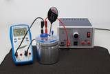 The image shows an experiment kit with a multimeter, which is used to measure current, and a power source that can provide both direct and alternating current. In the center is a container, presumably intended for experiments.
