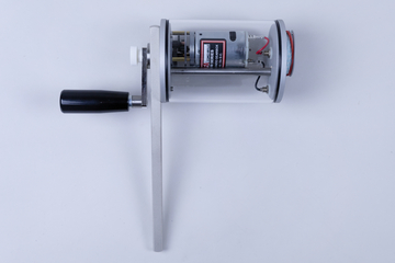 The image shows a transparent device with a handle and a motor inside. It appears to be designed for educational experiments, possibly to demonstrate mechanical motion or energy conversion.