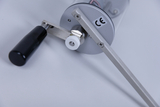 The image shows a mechanical device with a handle and a belt drive, probably used for conducting experiments in school education. It bears a CE mark, indicating safety standards.