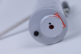 The image shows an experimental device with a round, silver casing and several connectors. A label indicating the device&#39;s purpose is located on the surface, while a transparent tube is connected to the device.