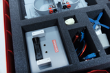 The picture shows a tidy experiment box containing various components such as battery compartments, cables and a small motor. The parts are organized in a protective foam insert to ensure optimal storage and transport.