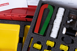 The picture shows an experiment kit with various materials such as magnets, rods, coils and small containers arranged in a padded foam insert. It is used to carry out experiments in an educational setting.