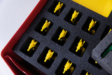 The picture shows a red box with a foam insert in which several yellow objects are arranged neatly. The yellow parts appear to be special holders or tools for experimental purposes in educational settings.