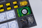 The picture shows an experiment kit that contains various materials for science classroom activities. These include a green compass card, several counting and measuring instruments, and small metal and plastic components.
