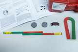 The picture shows an experiment kit for students that contains various magnetic materials such as bar magnets, round magnets and a U-shape. There is also a workbook that provides instructions and information on magnetic properties.