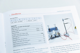The picture shows a page from a catalog for experimental supplies, on which the &quot;spark plug&quot; experiment is described. It shows technical data and materials, as well as an illustration of the corresponding experimental setup with connectable components.