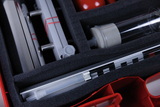 The picture shows a shelf on which various experimental materials for educational purposes are arranged. Among other things, you can see a transparent tube, metallic components and red elements that are probably used for chemical experiments.
