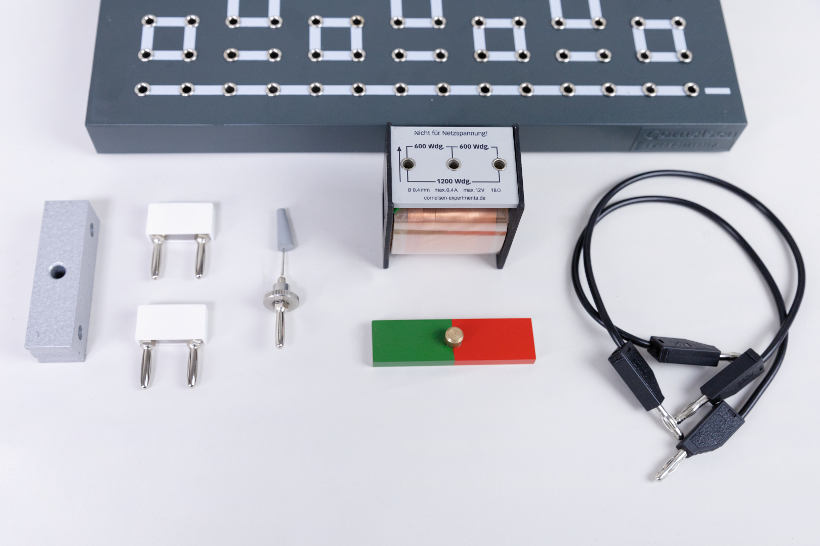 The picture shows various experimental components, including a connection terminal, two contact plates, a transformer and cables with plugs. These parts are designed for educational purposes and enable experimental work in science lessons.