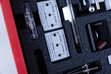 The picture shows a selection of experimental materials in a padded box, including measuring devices with different voltage readings. You can see several plugs and visible scales that can be used for school experiments.