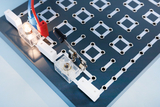 The picture shows an experiment board with visible electrical connections, on which there is a glowing lamp and a switch. The arrangement is optimized for carrying out electrical experiments in the educational sector.