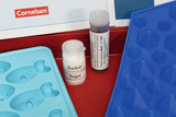 The picture shows a blue silicone mold with different shapes and two containers: one for sugar and one with red food coloring (E 129). These materials are part of an experiment set for the educational sector from Cornelsen.
