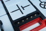 The picture shows a collection of experimental parts in a red storage case, intended for educational use in Germany. The parts include various circuits and components that can be used to experiment with electricity.