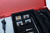 The picture shows a red case with various experimental components arranged in a foam-padded insert. You can see transparent cases, cables, a switch and a tool that can be used for scientific experiments.