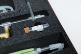 The picture shows a set of various experimental materials presented in a shock-resistant foam insert. The focus is on a test tube with a brown cap, surrounded by other laboratory equipment.