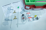 The picture shows a set for experiments in the field of water technology, consisting of various pipes, faucets, electrical components and a manual for instructions. All parts are neatly arranged and packed in a red container with foam insert.