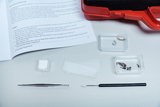 The picture shows materials for biological experiments, including insect samples and an experiment kit with tools such as tweezers and a scalpel. There is also a textbook with questions on insect anatomy on the table.