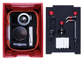 The picture shows a red storage box equipped with various experimental materials. The box contains, among other things, glassware, tubes and a metal part that can be used for chemical experiments in educational settings.
