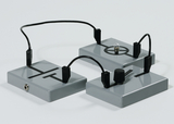 The image shows three grey plates with different symbols and electrical connections. One of the plates contains a small light bulb, while another has a rotary control, indicating experimental use in education.